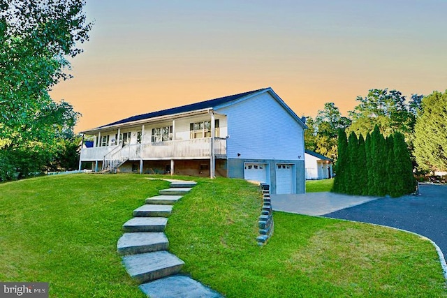 view of front of house with a garage, a lawn, and covered porch