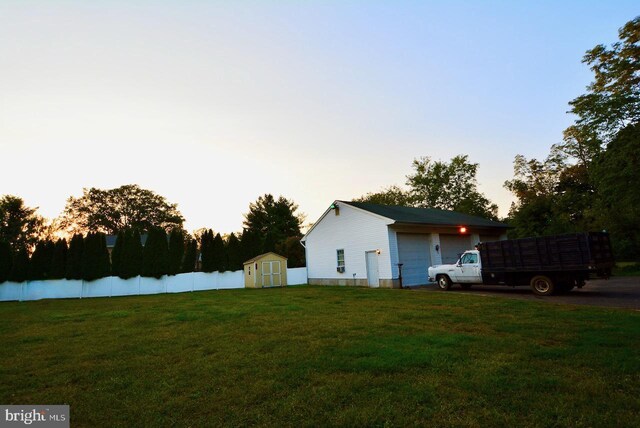 exterior space featuring a garage, a lawn, and a shed