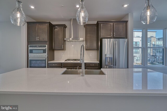 kitchen featuring dark brown cabinetry, appliances with stainless steel finishes, sink, and wall chimney range hood