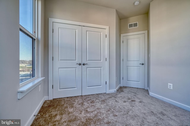 unfurnished bedroom featuring a closet and light colored carpet