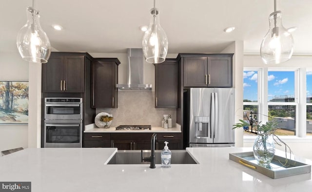 kitchen featuring wall chimney exhaust hood, appliances with stainless steel finishes, dark brown cabinetry, and sink