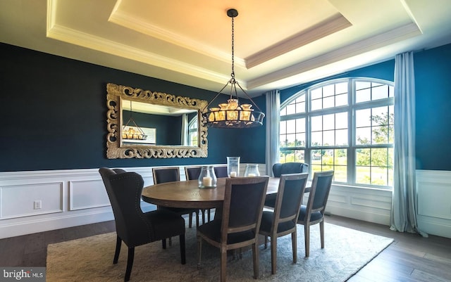 dining space featuring a raised ceiling, hardwood / wood-style floors, and crown molding