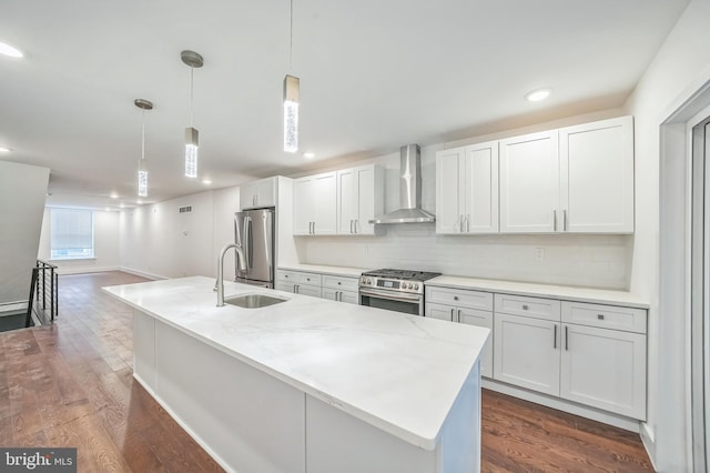 kitchen featuring hanging light fixtures, wall chimney exhaust hood, white cabinetry, and stainless steel appliances