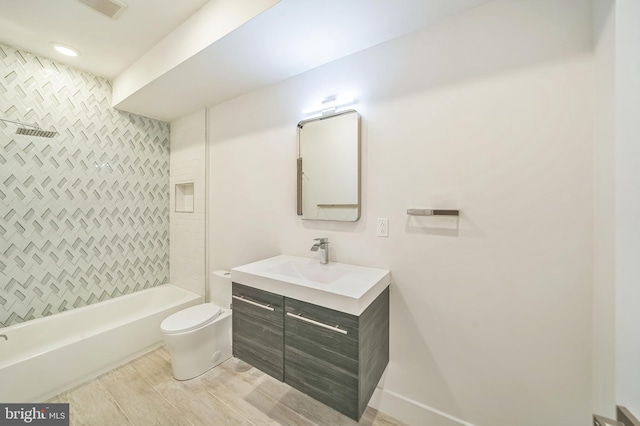 full bathroom featuring tiled shower / bath, vanity, and toilet