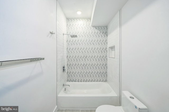 bathroom featuring tiled shower / bath combo and toilet