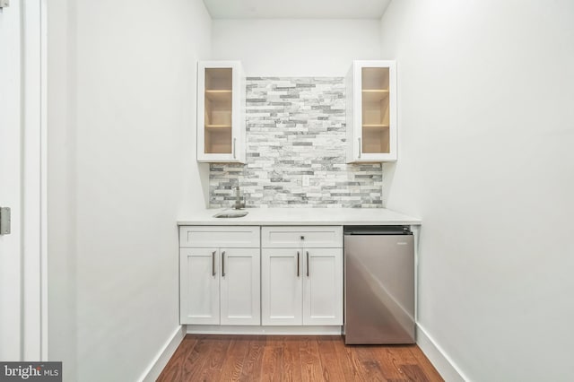 bar featuring hardwood / wood-style flooring, stainless steel fridge, tasteful backsplash, and white cabinetry