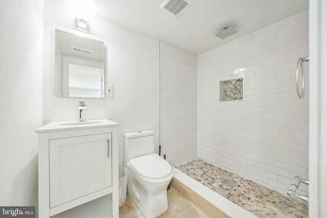 bathroom with tiled shower, vanity, and toilet