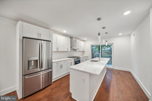 kitchen featuring white cabinetry, wall chimney exhaust hood, stainless steel appliances, a center island with sink, and light stone countertops