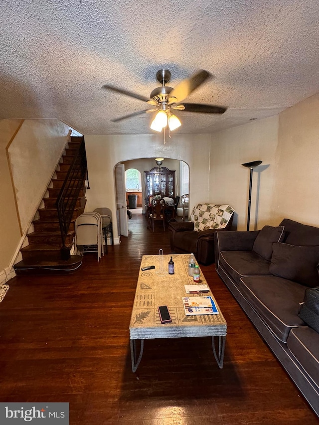 living room featuring ceiling fan, dark hardwood / wood-style floors, and a textured ceiling