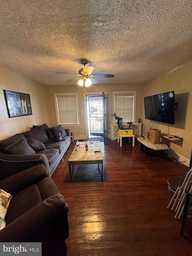 living room featuring ceiling fan, dark hardwood / wood-style floors, and a textured ceiling