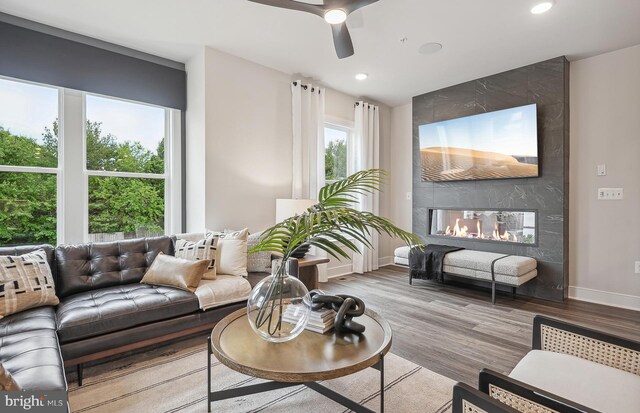 living room with a premium fireplace, ceiling fan, and hardwood / wood-style flooring