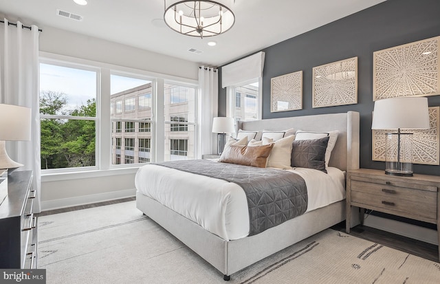 bedroom featuring light colored carpet, a chandelier, and multiple windows