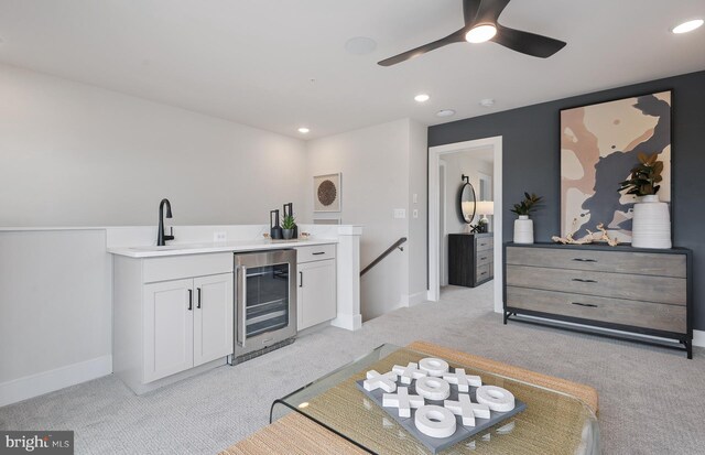 kitchen with light carpet, wine cooler, sink, and white cabinetry