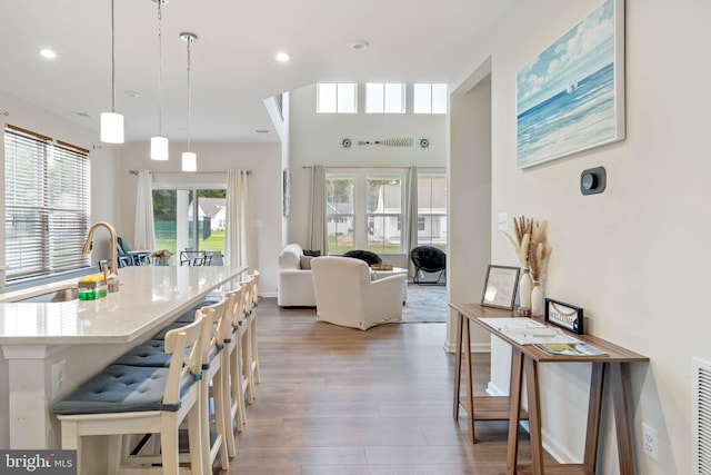 kitchen featuring wood-type flooring, decorative light fixtures, a kitchen bar, and sink