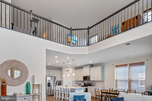 interior space with light hardwood / wood-style floors, a towering ceiling, and sink