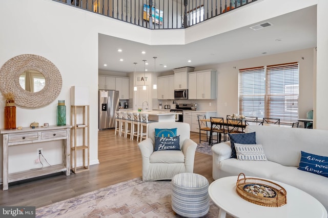 living room with a high ceiling, light hardwood / wood-style floors, and sink