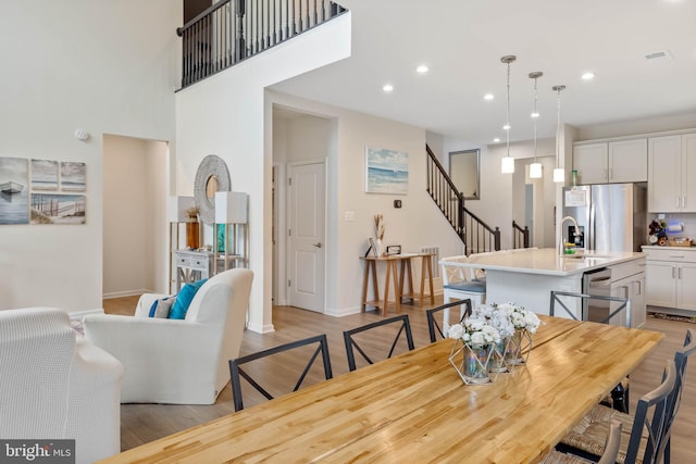 dining area featuring sink, light hardwood / wood-style floors, and a high ceiling