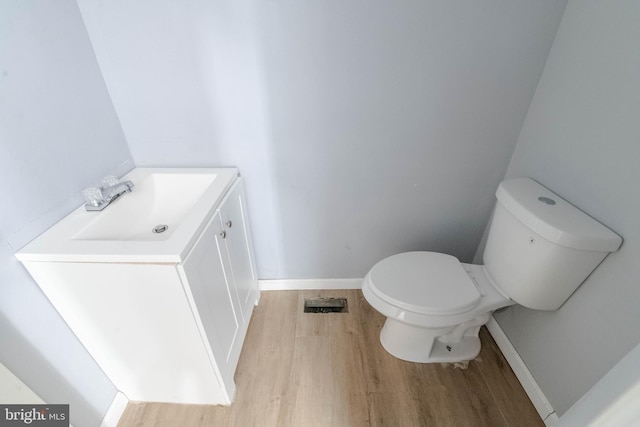 bathroom with hardwood / wood-style flooring, vanity, and toilet