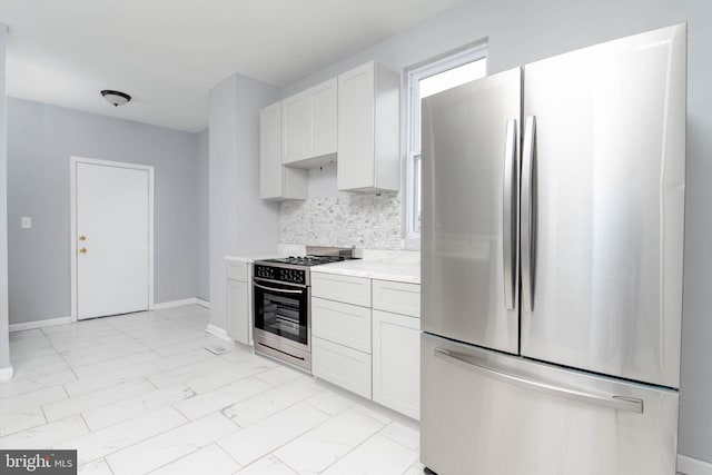 kitchen with white cabinets, appliances with stainless steel finishes, light stone countertops, and decorative backsplash