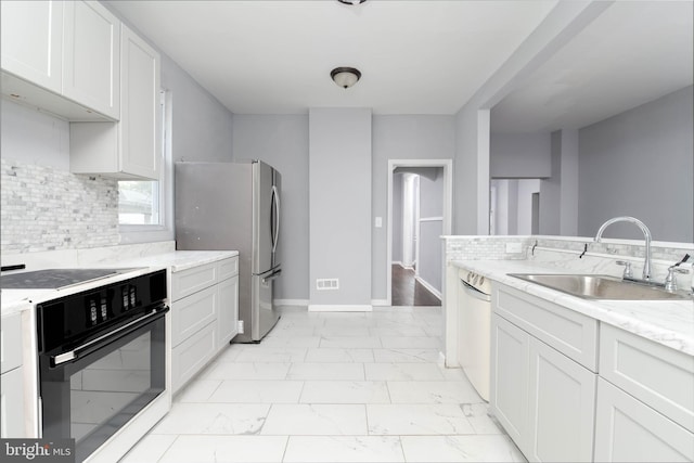 kitchen featuring oven, sink, light stone counters, and white cabinets