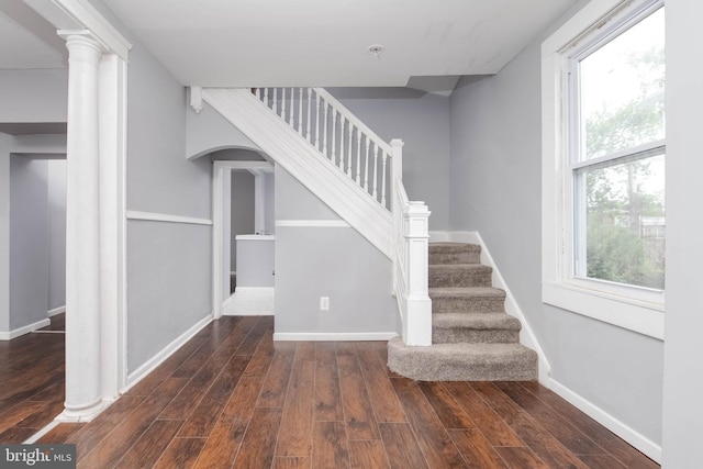 staircase with a wealth of natural light, hardwood / wood-style floors, and ornate columns