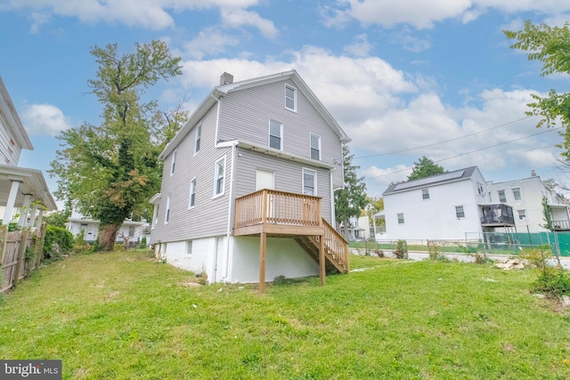 rear view of property featuring a wooden deck and a lawn