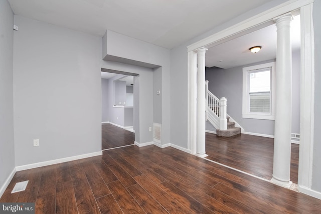 unfurnished bedroom featuring dark wood-type flooring and ornate columns