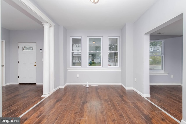 unfurnished room with ornate columns and dark hardwood / wood-style flooring