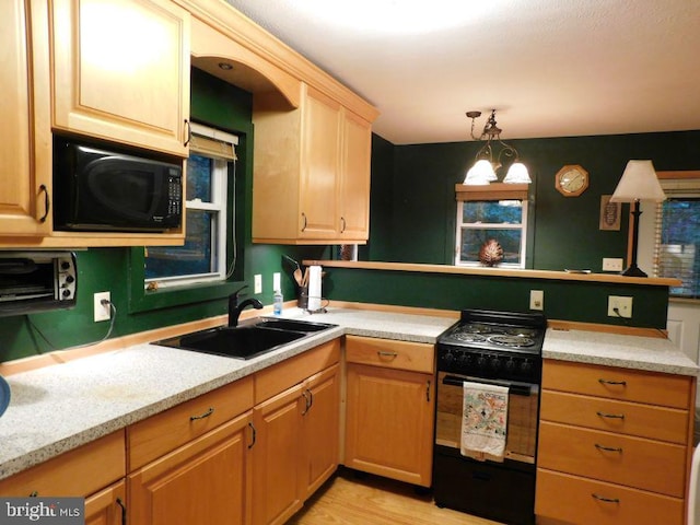 kitchen featuring black appliances, sink, light hardwood / wood-style floors, pendant lighting, and an inviting chandelier