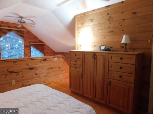 bedroom featuring wood walls, light wood-type flooring, and vaulted ceiling