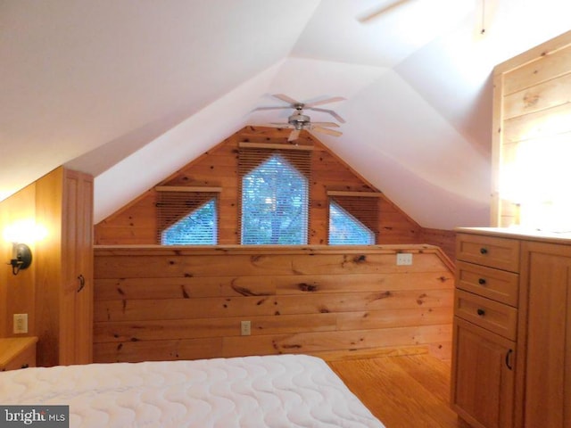 bedroom with lofted ceiling, multiple windows, light wood-type flooring, and wood walls