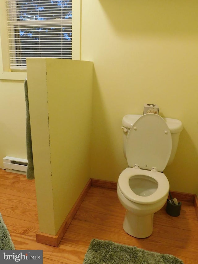 bathroom featuring baseboard heating, hardwood / wood-style flooring, and toilet