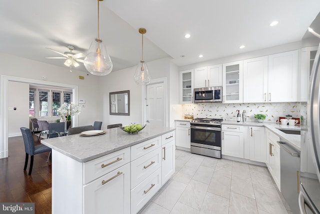 kitchen with appliances with stainless steel finishes, backsplash, ceiling fan, and white cabinets