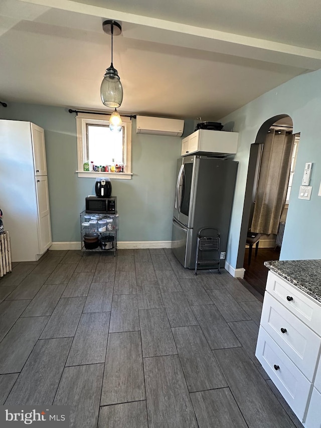 kitchen with dark stone counters, decorative light fixtures, white cabinets, dark hardwood / wood-style floors, and stainless steel refrigerator