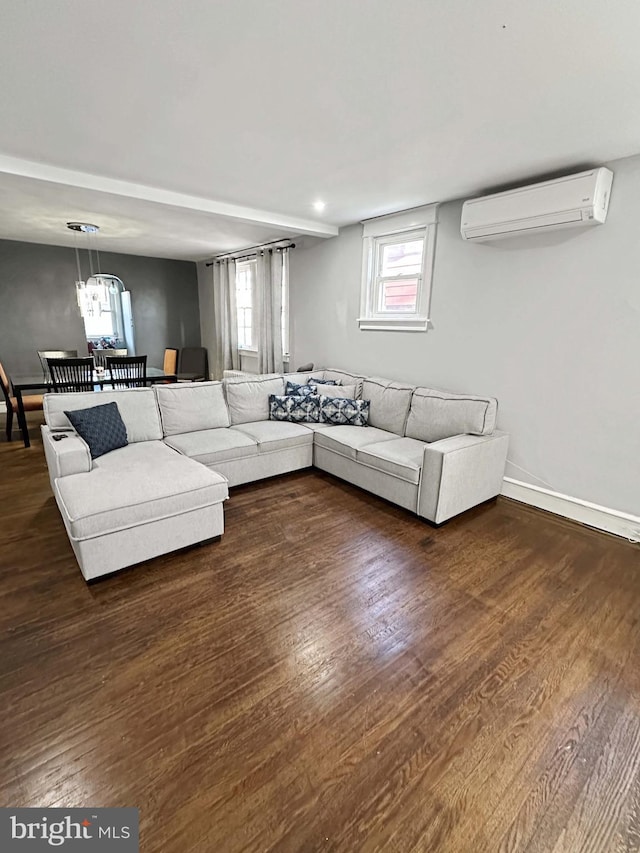 living room with a wall mounted air conditioner, an inviting chandelier, and dark wood-type flooring