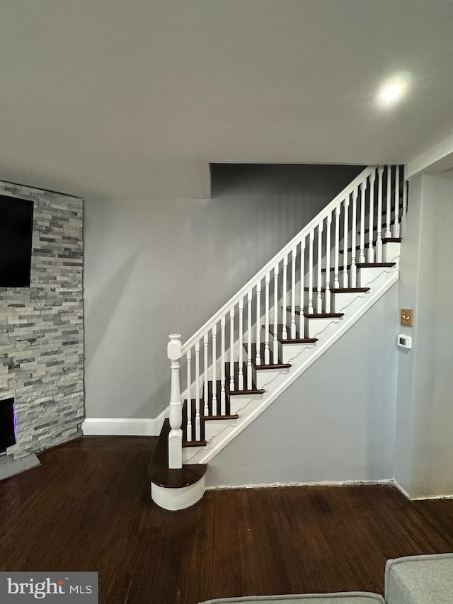 stairway featuring hardwood / wood-style floors and a stone fireplace