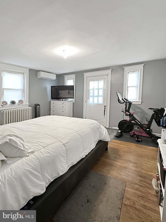 bedroom featuring radiator, dark hardwood / wood-style floors, and a wall mounted air conditioner