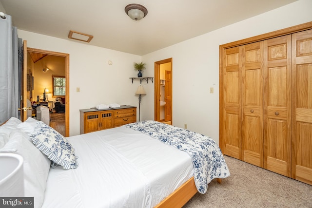 bedroom with ensuite bathroom, light colored carpet, and a closet