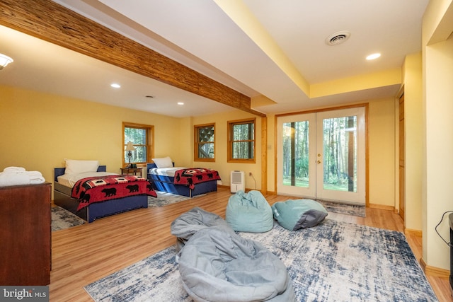 living room featuring beamed ceiling, light wood-type flooring, and a wealth of natural light