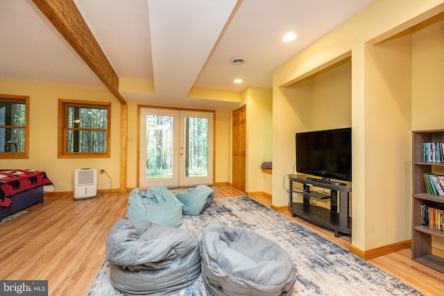 living room with light hardwood / wood-style flooring, beamed ceiling, and french doors