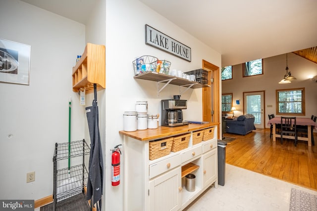 kitchen with light wood-type flooring, pendant lighting, and wooden counters