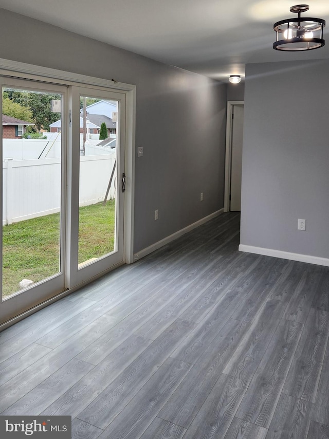 empty room with a notable chandelier, plenty of natural light, and dark hardwood / wood-style floors