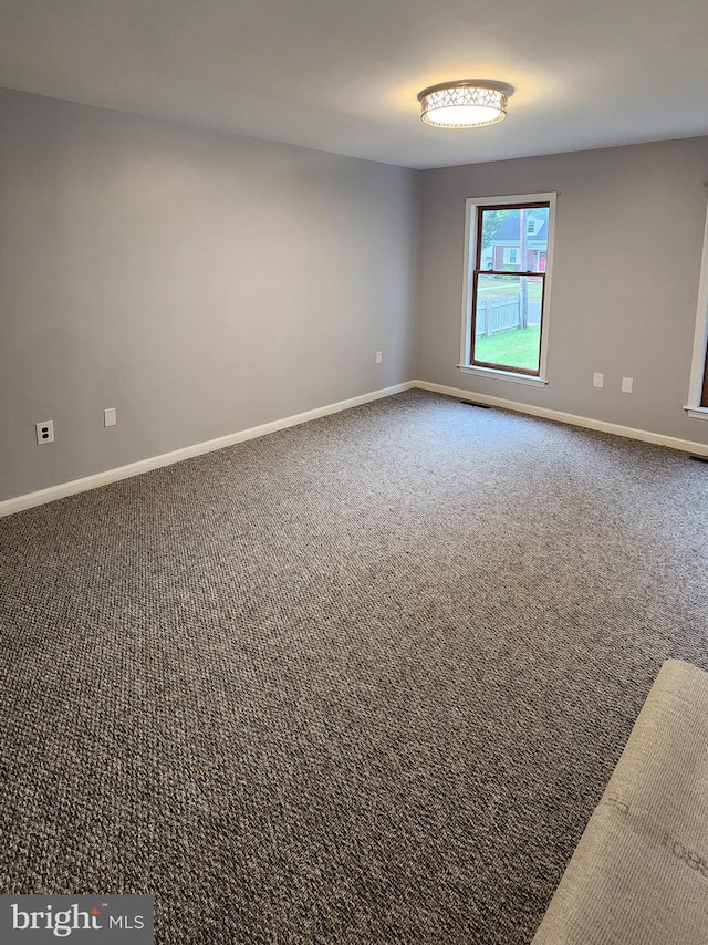 unfurnished room featuring dark colored carpet