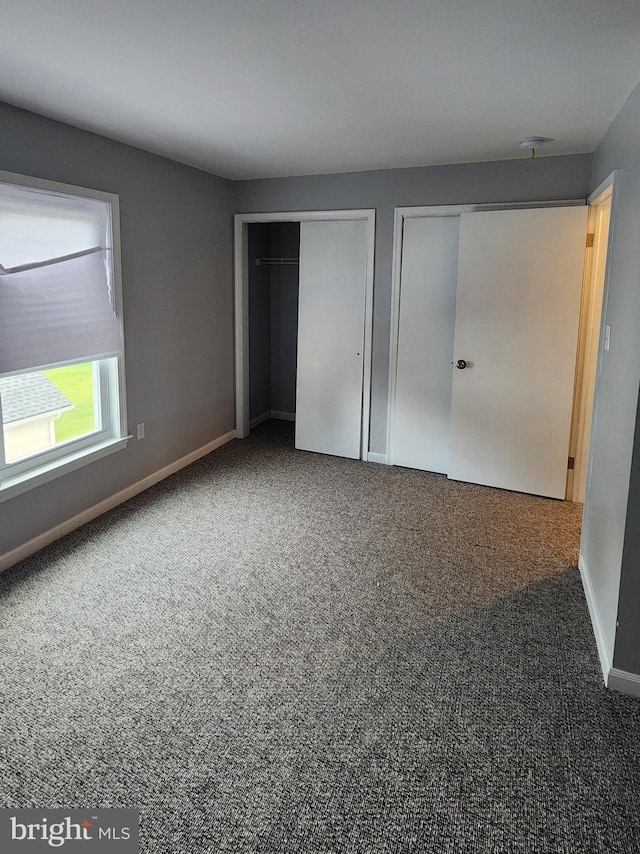 unfurnished bedroom with carpet floors and two closets