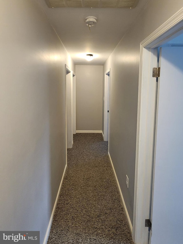 hall with dark colored carpet