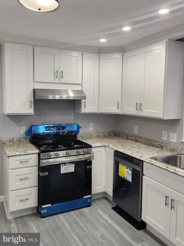 kitchen featuring light wood-type flooring, dishwasher, light stone counters, white cabinets, and stove