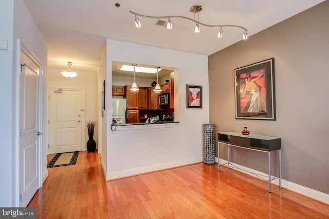 interior space featuring appliances with stainless steel finishes, hanging light fixtures, and light wood-type flooring