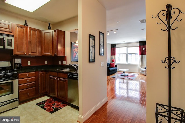 kitchen with light wood-type flooring, appliances with stainless steel finishes, and sink