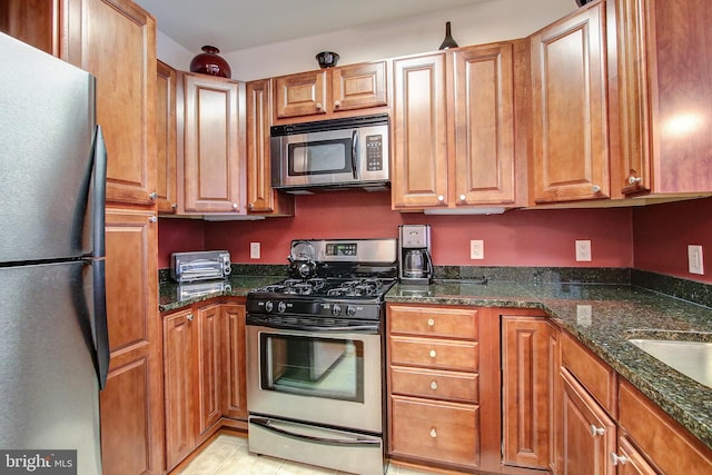 kitchen with dark stone countertops, stainless steel appliances, and light tile patterned floors