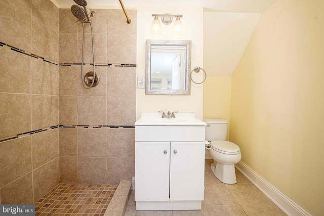 bathroom featuring vanity, tile patterned flooring, a tile shower, and toilet